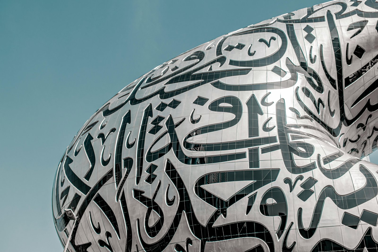 Home Close-up of the Museum of the Future in Dubai featuring stunning Arabic calligraphy under a blue sky.